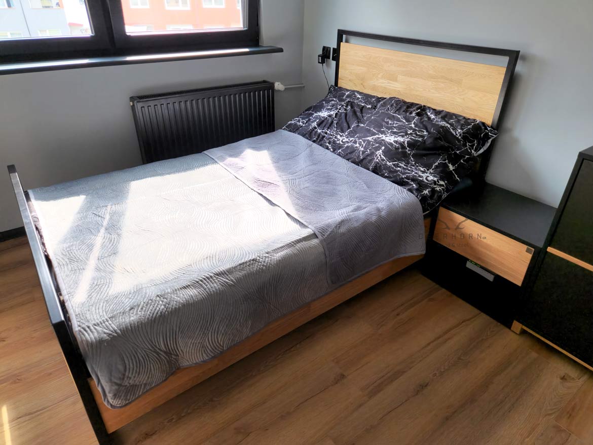 czarne łóżko z metalową ramą i drewnianym oparciem