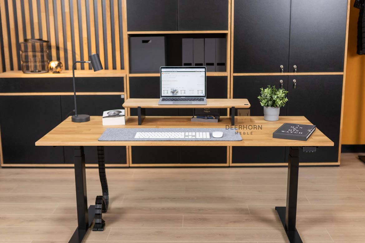 biurko z drewnianym blatem i metalowymi nogami, umieszczone w centralnym punkcie pomieszczenia, otoczone meblami biurowymi