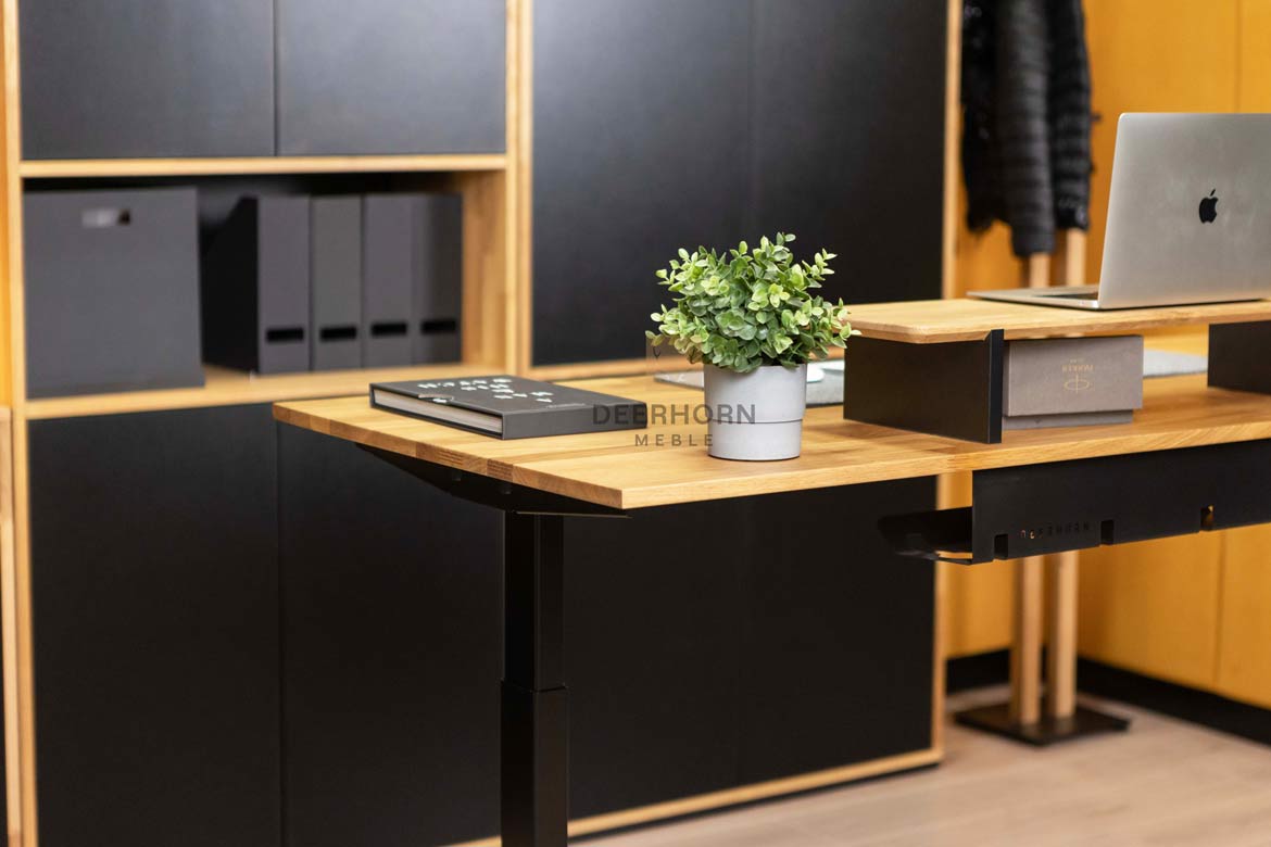 Biurko z eleganckim drewnianym blatem i stabilnymi metalowymi nogami, dominujące w otoczeniu mebli biurowych
