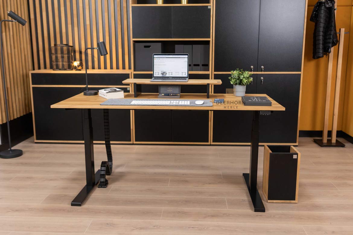 Biurko o nowoczesnym designie, z drewnianym blatem i metalowymi nogami, stojące w centralnym punkcie, w otoczeniu innych mebli biurowych