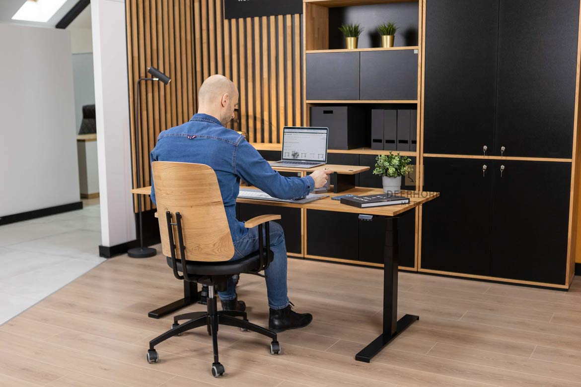 Biurko z eleganckim drewnianym blatem i solidnymi metalowymi nogami, dominujące w wystroju pomieszczenia, w którym umieszczone są inne meble biurowe