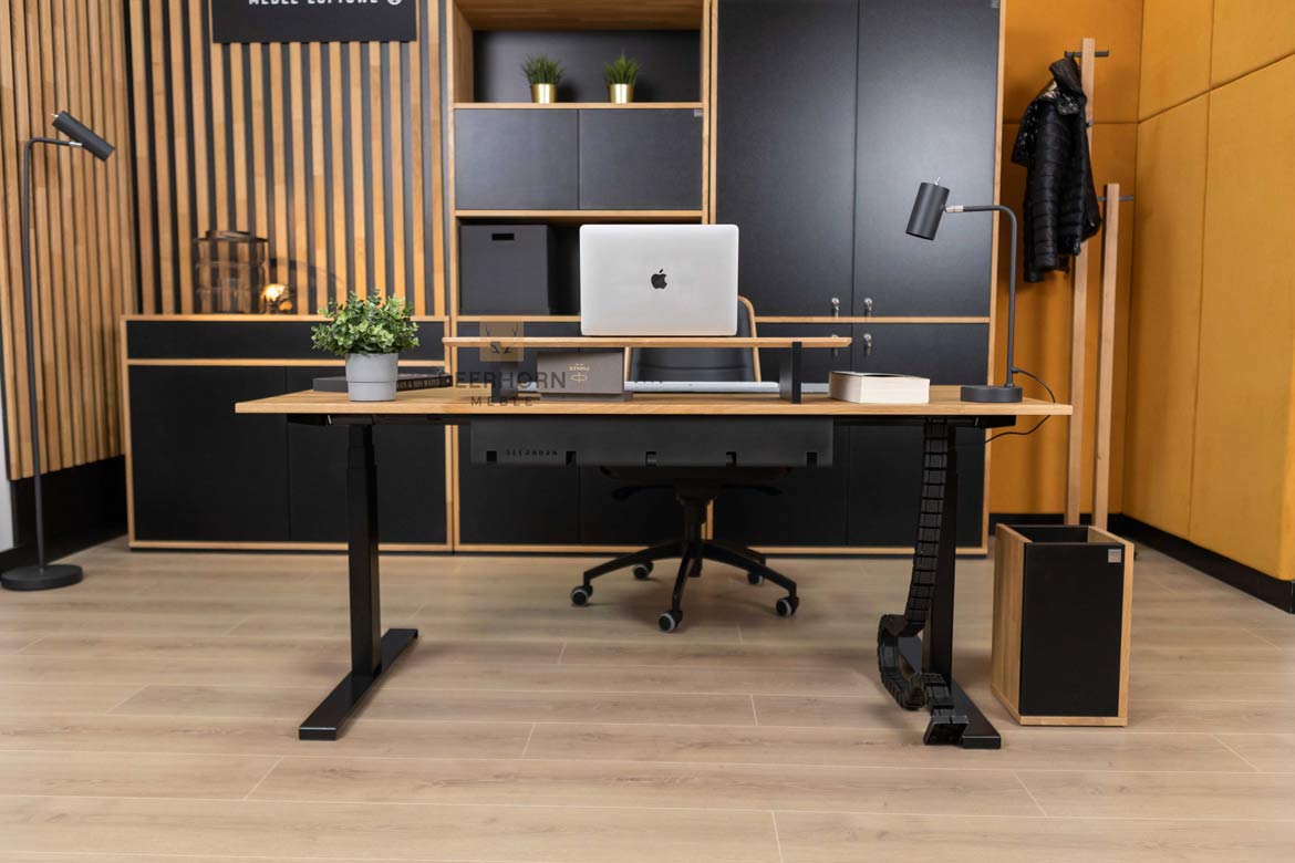 Biurko z drewnianym blatem i metalowymi nogami, umieszczone centralnie, pełniące funkcję głównego punktu w pomieszczeniu, w którym znajdują się inne meble biurowe