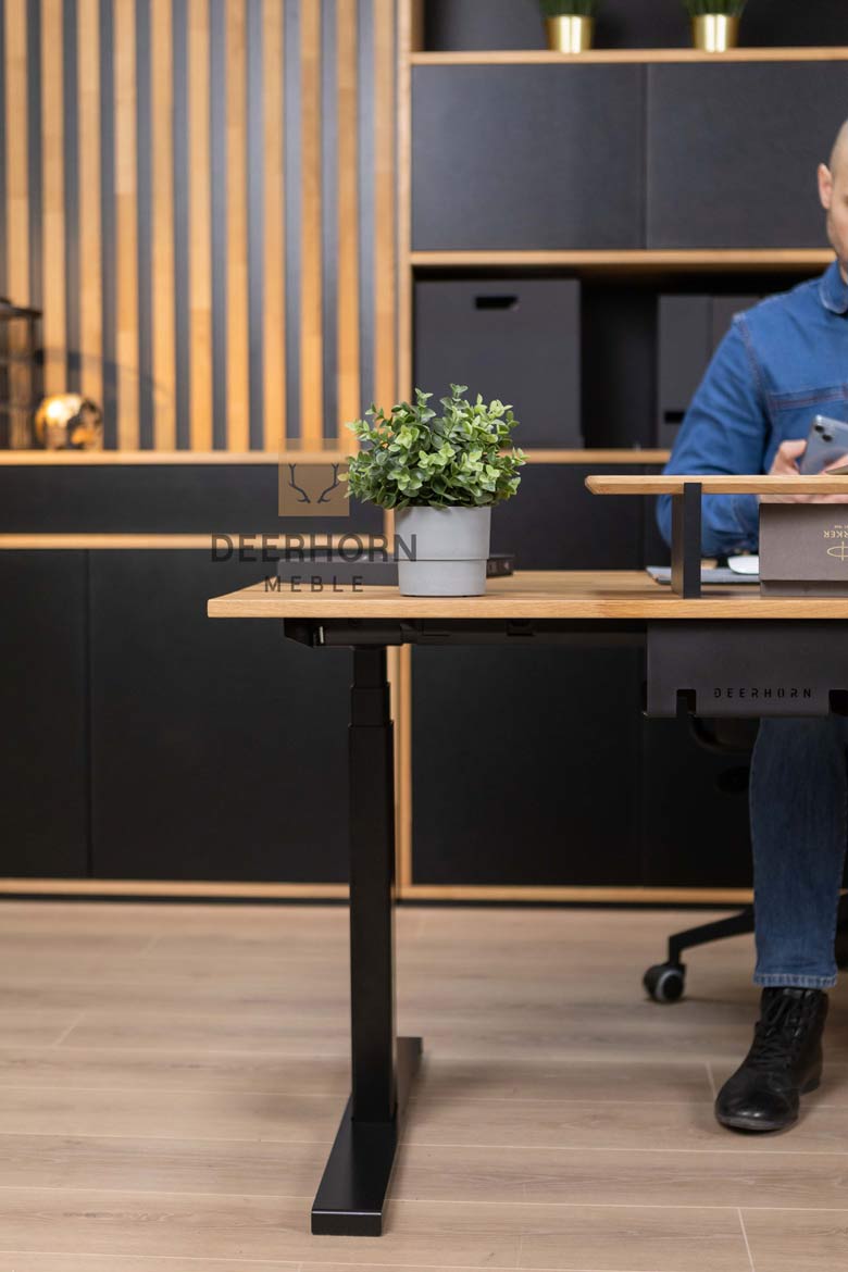Biurko o nowoczesnym designie, z drewnianym blatem i metalowymi nogami, będące głównym elementem aranżacji pomieszczenia, w którym znajdują się inne meble biurowe