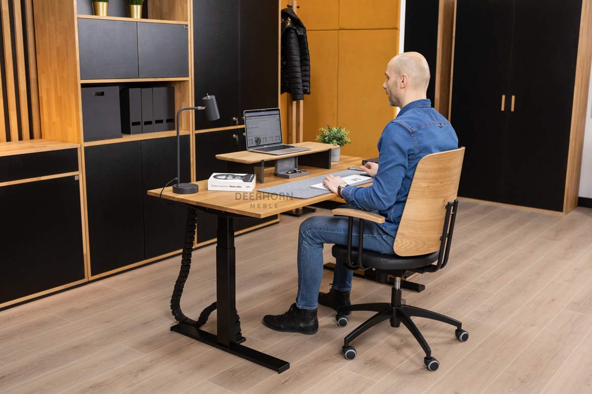 Biurko z trwałym drewnianym blatem i wytrzymałymi metalowymi nogami, zdobiące pomieszczenie, w którym dominują inne meble biurowe