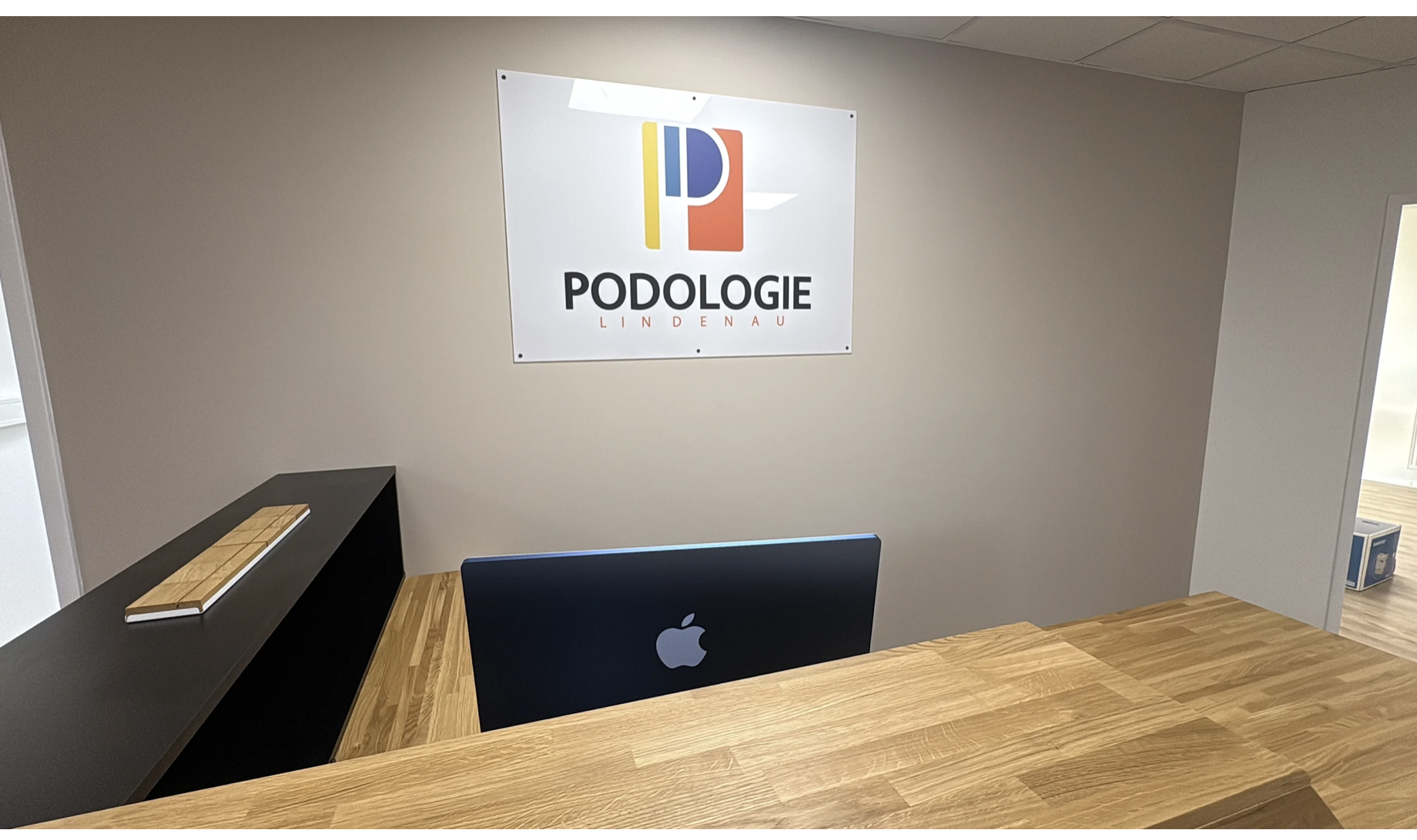 Drewniana lada recepcyjna z czarnymi elementami w klinice Podologie Lindenau