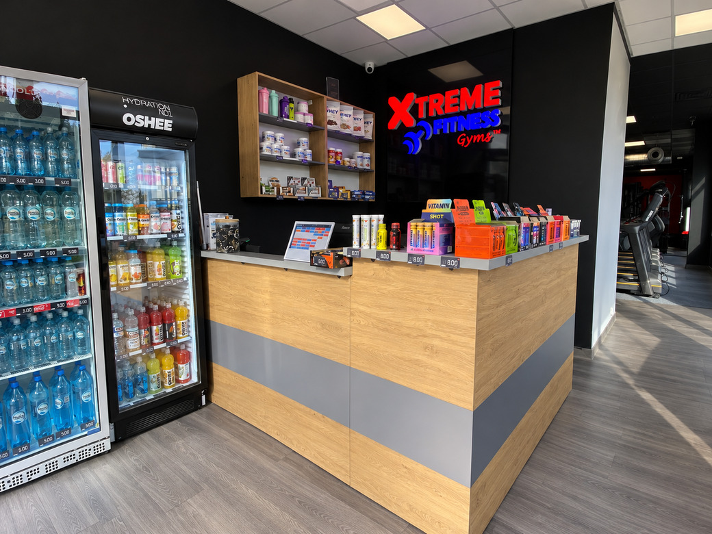 Lada recepcyjna z płyty meblowej z szarymi elementami do klubu Xtreme fitness