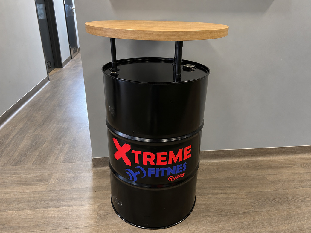 Stolik z beczki z drewnianym blatem jako mebel do strefy klubu fitness